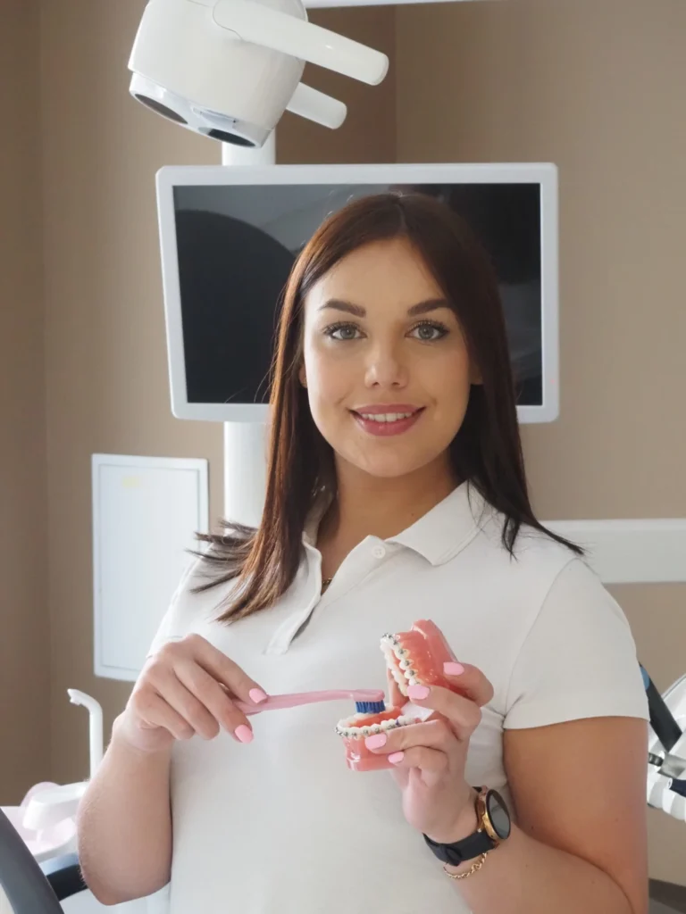 Zdjęcie przedstawia higienistkę Karolinę, która pokazuje jak dbać o higienę jamy ustnej