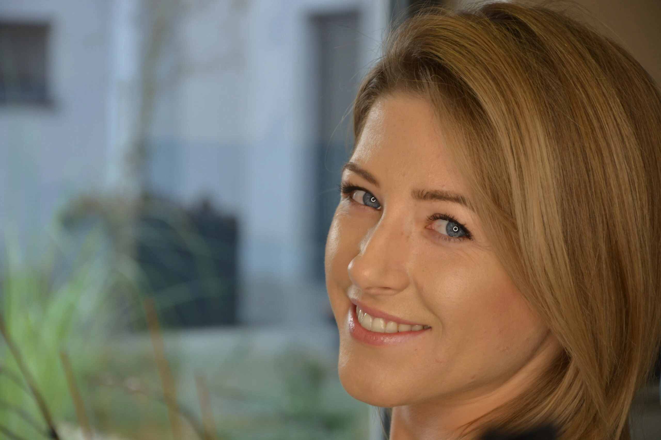 Zdjęcie przedstawia uśmiechniętą pacjentkę po leczeniu w gabinecie Ortos